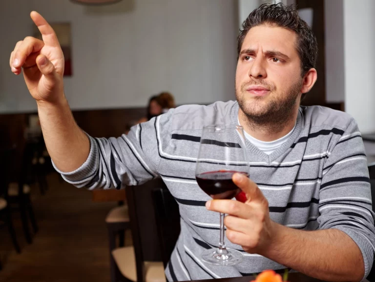 Client mécontent de son verre de vin entrain d'appeler le serveur pour se plaindre