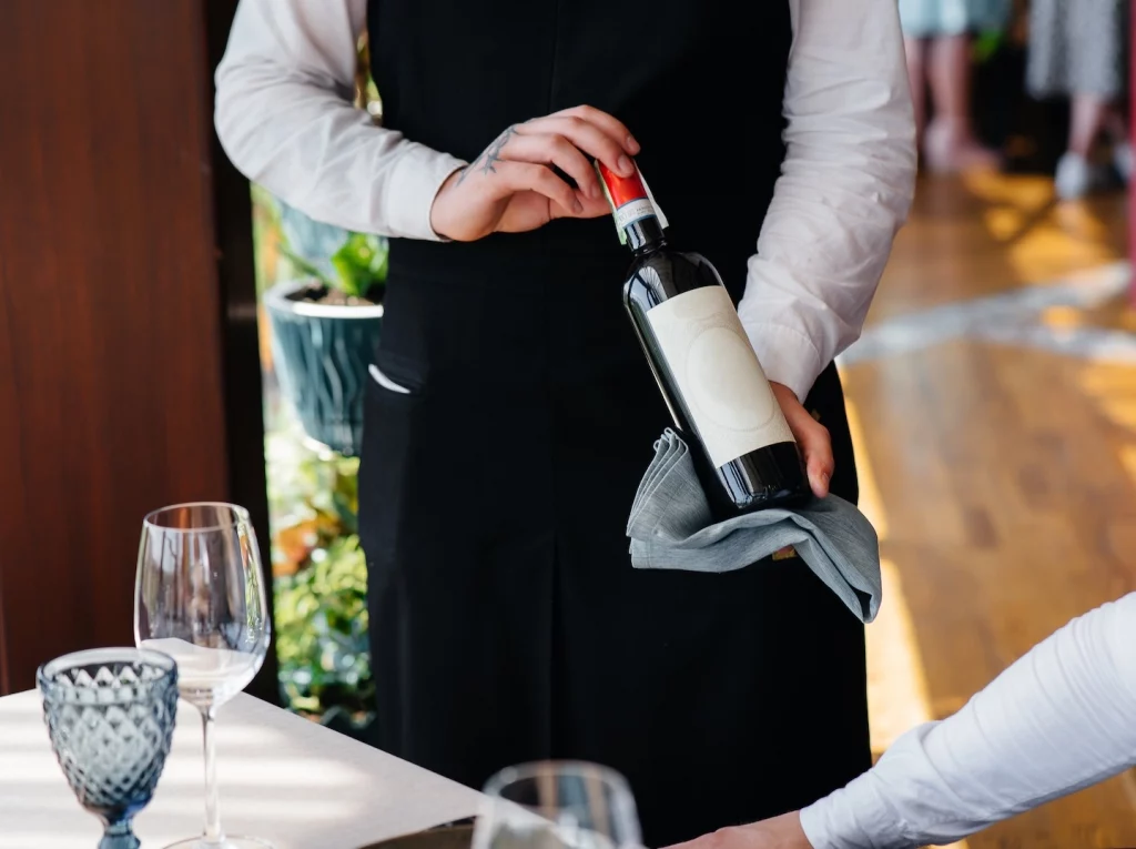 Sommelier présentant une bouteille de vin rouge à son client avant de l'ouvrir et attentant son acquiescement.